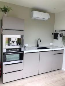 a white kitchen with a sink and a stove at Tussen de paarden @ De Hoeveschuur in Riemst