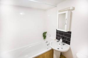 a white bathroom with a sink and a bath tub at The Basement in Exeter