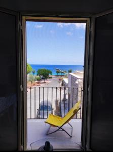 een gele stoel op een balkon met uitzicht op de oceaan bij Casa Levante in Isola delle Femmine