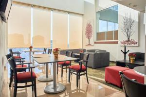 a restaurant with tables and chairs and windows at La Quinta by Wyndham Puebla Palmas Angelopolis in Puebla