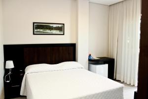 een slaapkamer met een groot wit bed en een tafel bij Blue Hill Hotel in Timbó