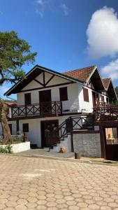 uma casa com um cão sentado à frente dela em Pousada Chales Monte Verde em Monte Verde