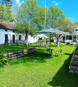 a patio with a table and an umbrella in the grass at Gysinge Wärdshus Hotell in Österfärnebo