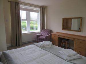 a bedroom with a bed and a desk and a mirror at Marr Cottage in Thornhill