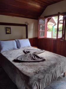uma cama com um cobertor num quarto em Pousada Chales Monte Verde em Monte Verde