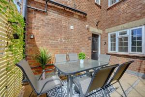 a table and chairs on a patio with a brick wall at Brewery Loft - 3 Bedroom Bright Spacious apartment in the centre of town, Wifi, Netflix in Cirencester