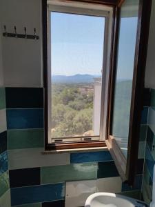 een badkamer met een raam en een toilet met uitzicht bij Sa Dommu 'e su coro in Triei