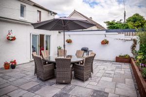 a table and chairs with an umbrella on a patio at Amazing views across the Moray Firth, Private Suntrap Patio, 300m from the Beach, off street parking! in Nairn