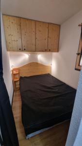 a small bedroom with a black bed in a room at Appartement de station rénovée avec parking in Habère-Poche