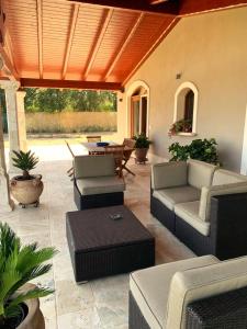 un patio al aire libre con sofás, mesa y sillas en Corte dei Mirti, Appartamento indipendente con ampia veranda, en Iglesias
