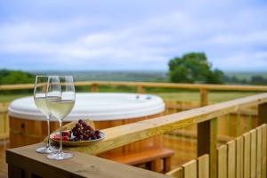 a glass of wine and a bowl of grapes on a wooden table at Luxury Log Cabin with a Hot Tub in Stone