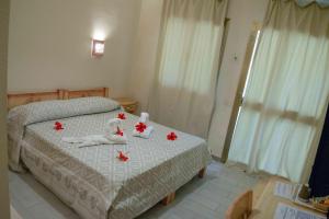 a bedroom with a bed with red flowers on it at Hotel L'Oleandro in Villasimius