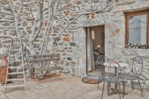 un patio con mesa y sillas junto a una pared de piedra en Maison d'hôtes Le Hameau de la Mûre, en Saint-Laurent-du-Pape