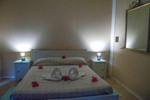 two swans are laying on a bed with red flowers at Hotel L'Oleandro in Villasimius