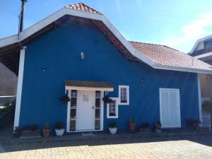 una casa azul con una puerta blanca en Aconchego Do Lar, en Campos do Jordão