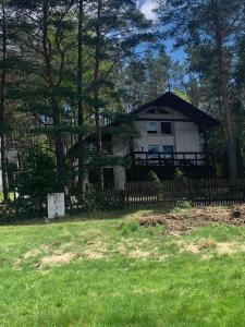 una casa con una valla delante de un patio en Domek Między Jeziorami en Wąglikowice