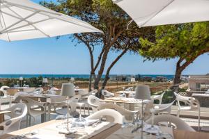ein Restaurant mit weißen Tischen, Stühlen und Sonnenschirmen in der Unterkunft Perla Saracena Hotel & Restaurant in Salve