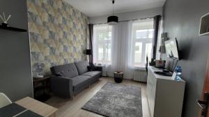 uma sala de estar com um sofá e uma televisão em Pokoje przy Arkadii em Suwałki