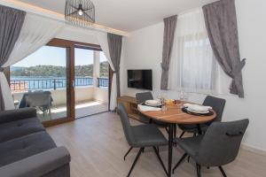 ein Wohnzimmer mit Tisch und Stühlen und einem Fernseher in der Unterkunft Villa Maestral in Vinišće