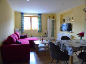 sala de estar con sofá rosa y mesa en Ferienwohnung Csilla 2 en Oberweid