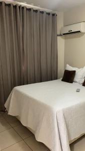 a bedroom with a white bed and a curtain at FlatsRose CH Flamboyant Conforto e qualidade in Goiânia +6 photos