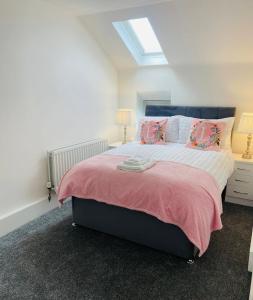 a bedroom with a large bed with pink sheets and pillows at Ballycastle Town Centre Studio Apartment in Ballycastle