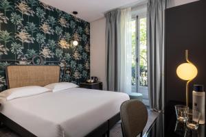 una camera da letto con un grande letto bianco e una finestra di Hotel De Suez a Parigi