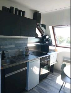 uma cozinha com um fogão, um lavatório e uma janela em Appartement 45m2 - Proche Deauville - Vue Mer em Bénerville-sur-Mer