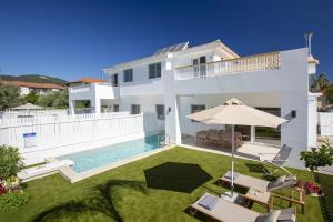 a white house with a swimming pool and an umbrella at THE QUAD Luxury Villas in Lygia