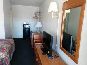 Habitación de hotel con TV y escritorio con espejo. en Economy Inn Safford, en Safford