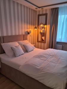 a large bed with white sheets and pillows in a bedroom at Grand Royal Apartment Premium in Gdańsk