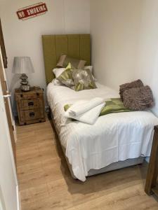 a bedroom with a bed with white sheets and a lamp at Linnaea Rooms - Corston Nr Malmesbury in Malmesbury