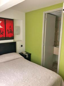 1 dormitorio con paredes verdes, 1 cama y teléfono en Hotel Ruah, en Cuernavaca