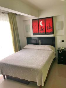 a bedroom with a bed and two paintings on the wall at Hotel Ruah in Cuernavaca