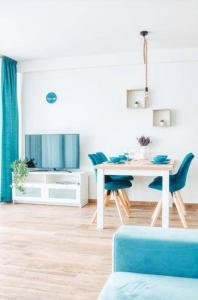 een woonkamer met een tafel en blauwe stoelen bij 365Balaton Apartmanok in Alsóörs