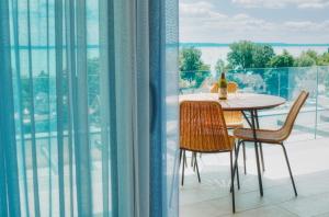 a table and chairs on a balcony with a view at 365Balaton Apartmanok in Alsóörs