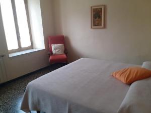 een slaapkamer met een bed en een rode stoel bij La locanda di nonna Jolanda in Borgo a Mozzano