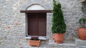 un edificio de piedra con una ventana y dos macetas en Αντίρρινο - Guest house, en Arachova