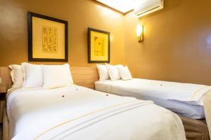 two beds in a hotel room with white sheets at The Lemonary Marrakech in Marrakech