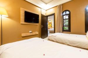 a bedroom with two beds and a flat screen tv at The Lemonary Marrakech in Marrakech