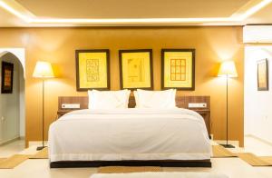 a bedroom with a large white bed with three pictures on the wall at The Lemonary Marrakech in Marrakech