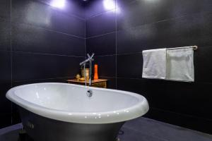 a bathroom with a white tub and a black wall at The Lemonary Marrakech in Marrakech
