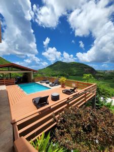 a wooden deck with a swimming pool and mountains at flamboyantvilla in Gros Islet