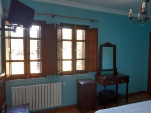 a bedroom with blue walls and windows and a mirror at Casa Rural dos Chaos in Arnoia