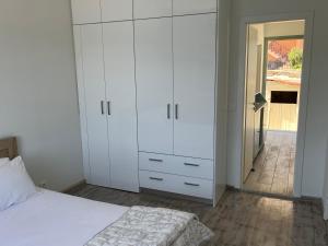 a bedroom with white cabinets and a white bed at Modern cottage on the sea in Vathi