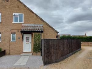 a brick house with a white door and a fence at 1 Bedroom House with Garden and off road private parking in Peterborough