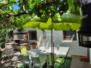 a table and chairs under a green umbrella at CASA JUNTO AL PARQUE NATURAL DE LAS BARDENAS in Sádaba
