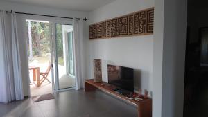 een woonkamer met een tv en een glazen schuifdeur bij Villa Cap Ouest Piscine Grand Jardin à 2 Pas de l'Océan in Cap Skirring