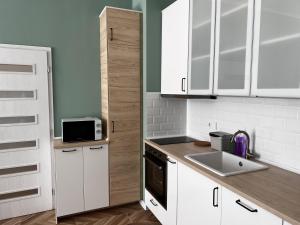 uma cozinha com armários brancos, um lavatório e um micro-ondas em Las Brisas Garden Apartment em Burgas