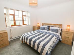 a bedroom with a bed and two night stands and a window at Yr Hen Efail in Cemaes Bay